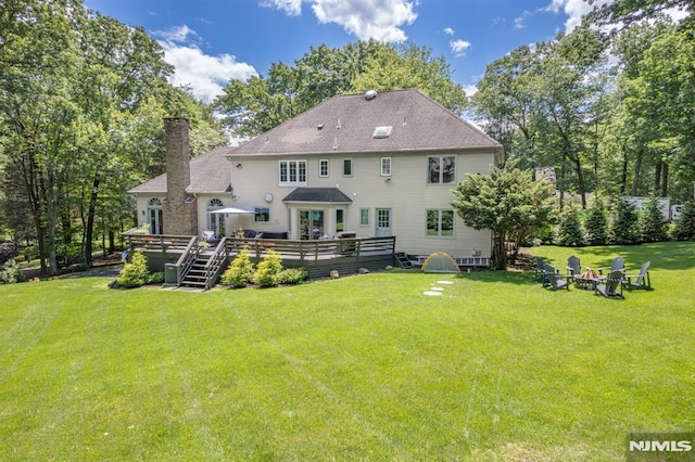 rear view of house with a lawn, an outdoor fire pit, and a wooden deck