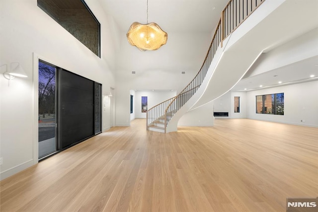 foyer entrance featuring a towering ceiling and light wood-type flooring