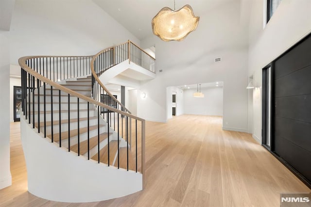 stairway with hardwood / wood-style flooring and a high ceiling