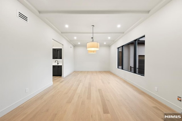 interior space with sink, beam ceiling, and light hardwood / wood-style floors