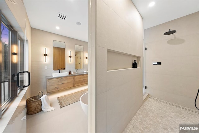 bathroom with vanity, tile walls, and walk in shower