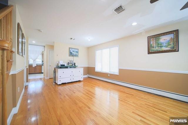 interior space with a baseboard radiator, light wood-type flooring, and ceiling fan