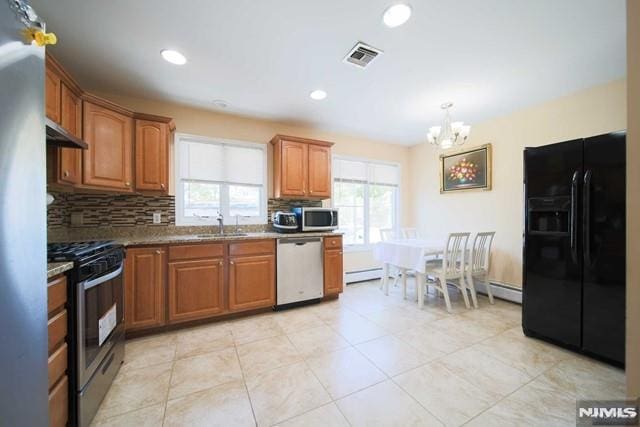 kitchen with light stone countertops, stainless steel appliances, tasteful backsplash, sink, and light tile patterned floors