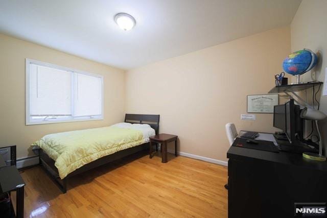 bedroom with hardwood / wood-style floors and baseboard heating