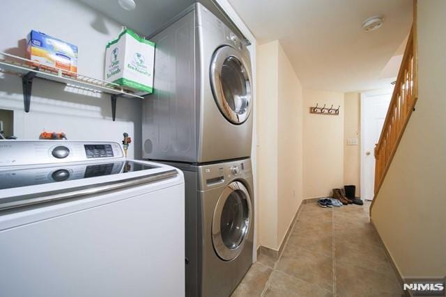 laundry room featuring stacked washer / dryer and light tile patterned flooring