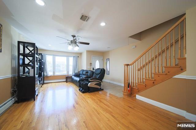 unfurnished living room with hardwood / wood-style floors and a baseboard heating unit