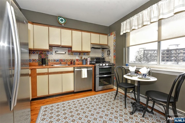 kitchen with stainless steel appliances, tasteful backsplash, cream cabinets, and sink