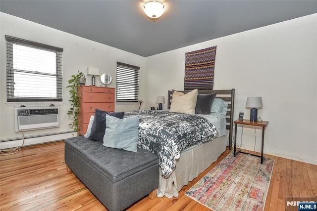 bedroom with hardwood / wood-style floors, a baseboard heating unit, and a wall mounted AC