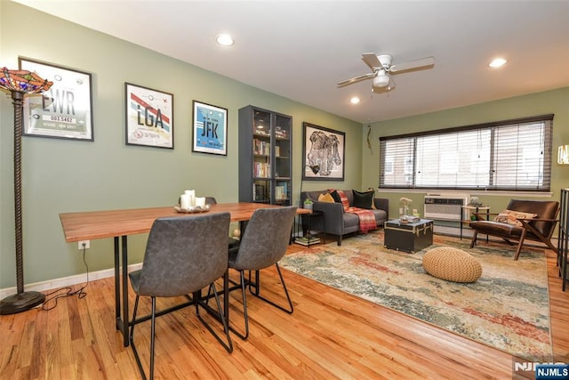 dining space with ceiling fan, light hardwood / wood-style floors, and a wall mounted AC