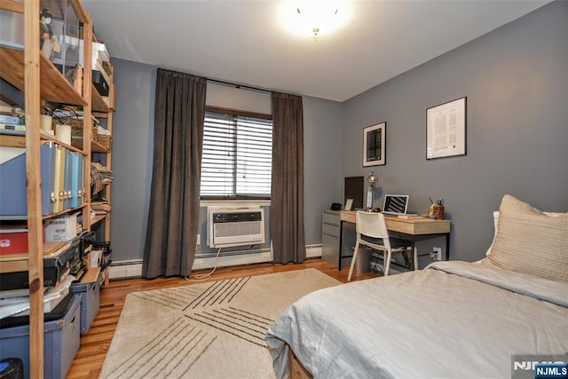 bedroom with a baseboard heating unit and light hardwood / wood-style floors