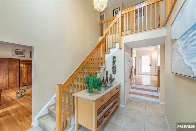 stairs featuring a chandelier, a high ceiling, and tile patterned flooring