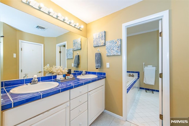 bathroom with tiled tub, tile patterned floors, and vanity