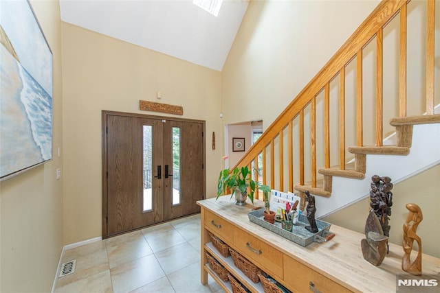 tiled entryway with high vaulted ceiling and french doors