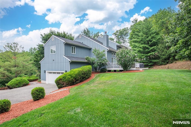 view of front of property with a garage, a wooden deck, and a front yard