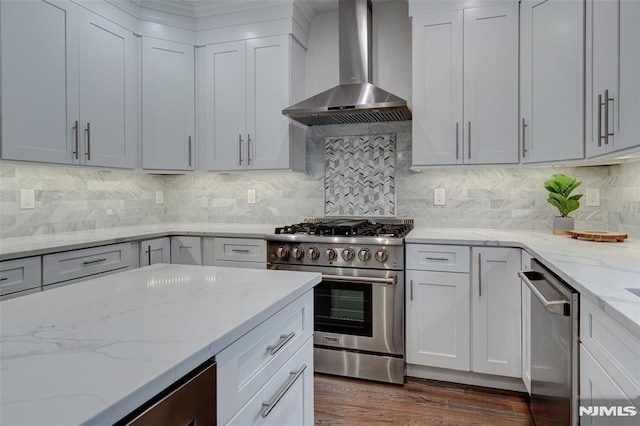 kitchen featuring decorative backsplash, light stone counters, wall chimney range hood, and stainless steel appliances