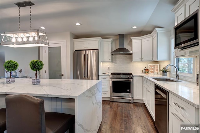 kitchen with a kitchen breakfast bar, sink, pendant lighting, wall chimney exhaust hood, and high quality appliances