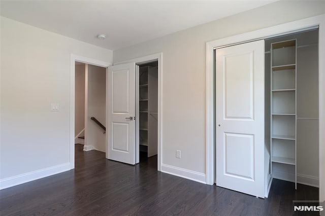 unfurnished bedroom featuring a closet and dark wood-type flooring