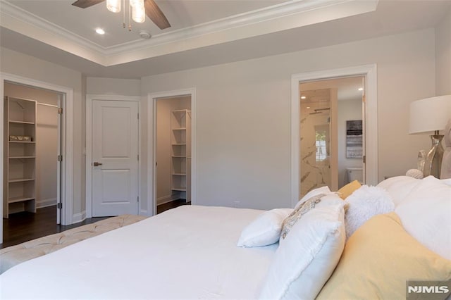 bedroom featuring ensuite bath, a walk in closet, a closet, a raised ceiling, and ceiling fan