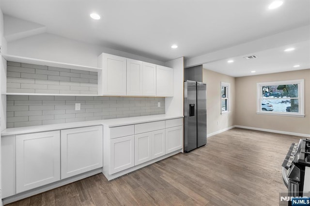 kitchen featuring white cabinets, appliances with stainless steel finishes, light hardwood / wood-style flooring, and tasteful backsplash