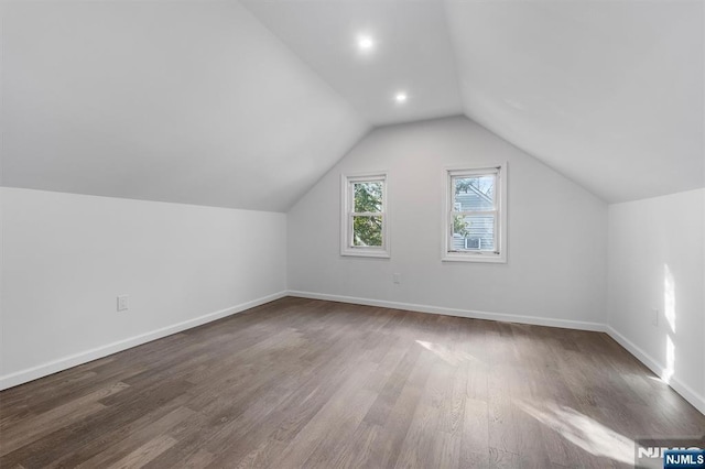 bonus room featuring vaulted ceiling and dark wood-type flooring