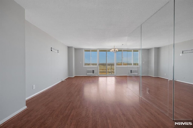 unfurnished living room featuring a wall of windows, a wall mounted air conditioner, a notable chandelier, and dark hardwood / wood-style flooring