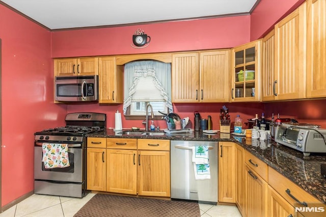 kitchen featuring sink, light tile patterned floors, stainless steel appliances, and dark stone counters