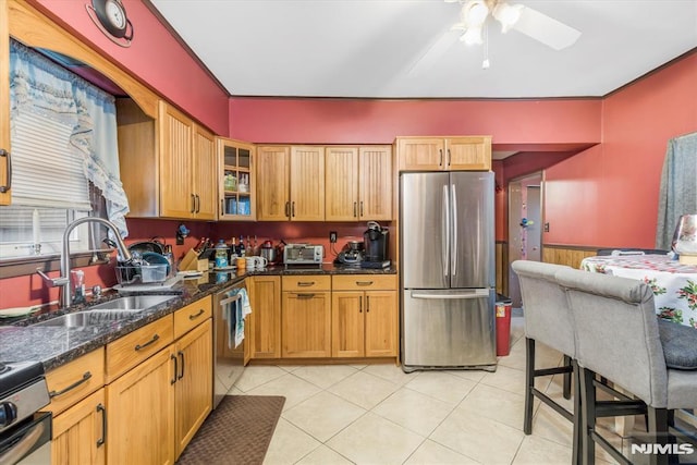 kitchen featuring light tile patterned flooring, sink, wood walls, dark stone countertops, and appliances with stainless steel finishes