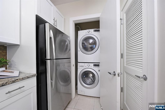 laundry room featuring laundry area, light tile patterned floors, and stacked washer and clothes dryer