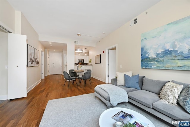 living area with wood finished floors, visible vents, and baseboards