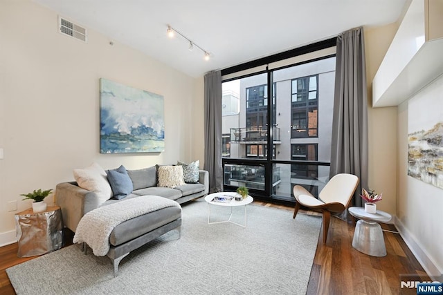 living area with wood finished floors, baseboards, visible vents, track lighting, and expansive windows