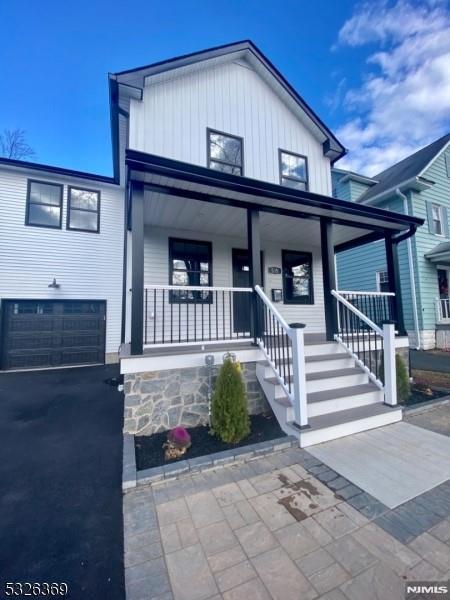 view of front of home featuring central AC, a porch, and a garage