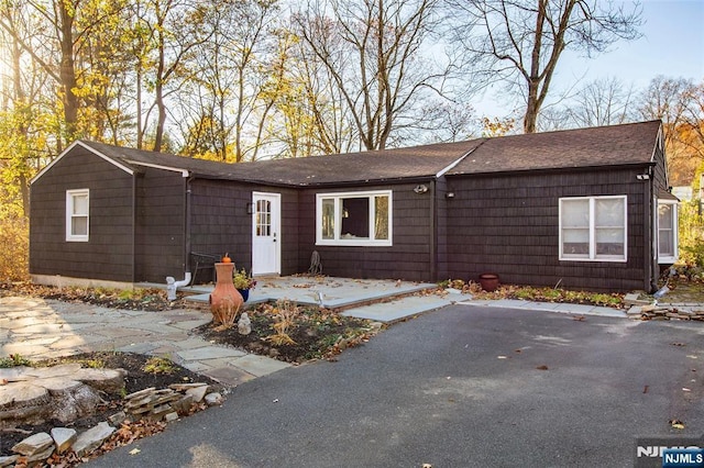 view of front of property featuring a patio area and a shingled roof