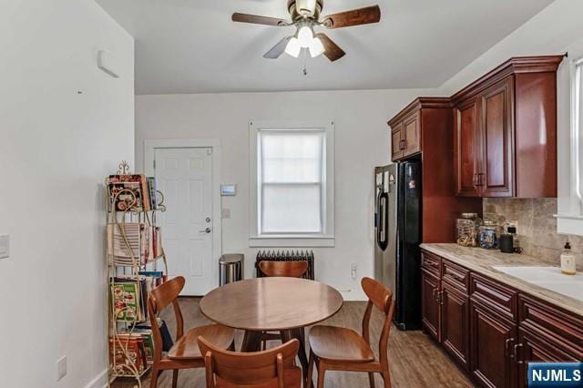 kitchen featuring sink, decorative backsplash, hardwood / wood-style flooring, ceiling fan, and black fridge