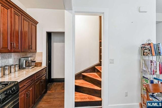 kitchen featuring light stone counters, backsplash, black range with gas cooktop, and dark wood-type flooring