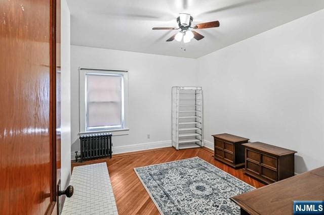 interior space with hardwood / wood-style flooring, ceiling fan, and radiator heating unit