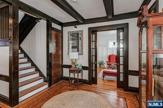 foyer featuring beam ceiling, ornamental molding, french doors, and hardwood / wood-style flooring