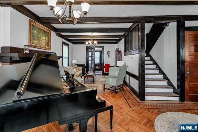 interior space with a notable chandelier, beam ceiling, and light parquet floors