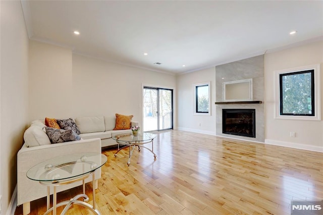 living room featuring a fireplace, light hardwood / wood-style flooring, and crown molding