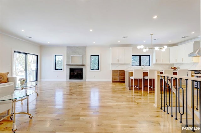 living room featuring a chandelier, a healthy amount of sunlight, light hardwood / wood-style flooring, and a high end fireplace