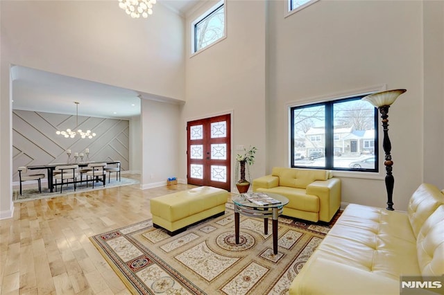 living room with a towering ceiling, a chandelier, and hardwood / wood-style floors