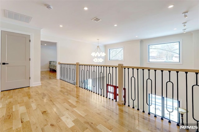 hallway with an inviting chandelier and light hardwood / wood-style floors