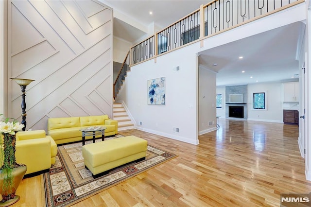 living room featuring light hardwood / wood-style floors, a high ceiling, and a large fireplace