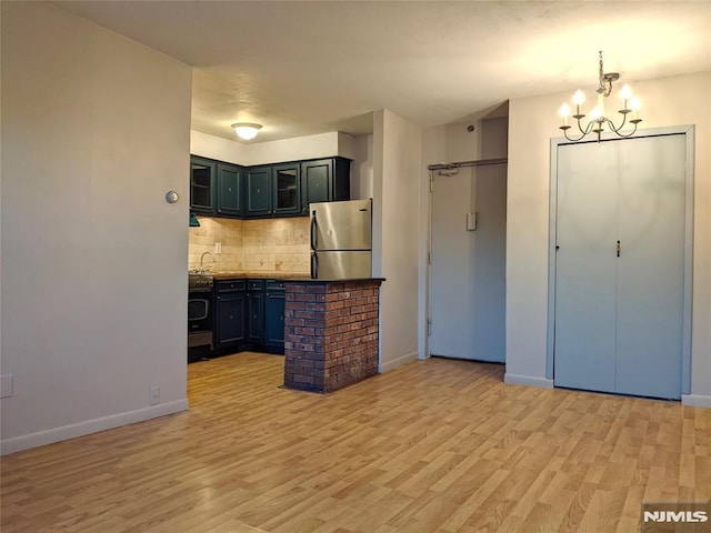 kitchen with an inviting chandelier, light hardwood / wood-style flooring, appliances with stainless steel finishes, and tasteful backsplash