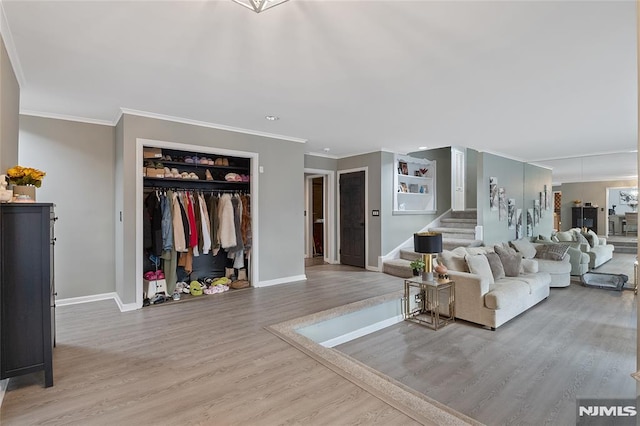 living room with built in features, light wood-type flooring, and ornamental molding