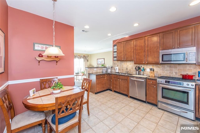 kitchen featuring hanging light fixtures, sink, dark stone countertops, decorative backsplash, and stainless steel appliances