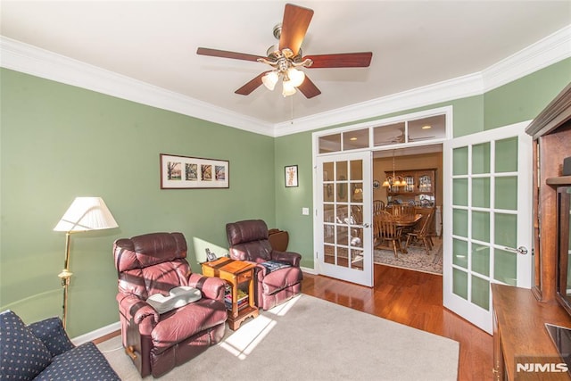 sitting room featuring crown molding, hardwood / wood-style flooring, ceiling fan with notable chandelier, and french doors