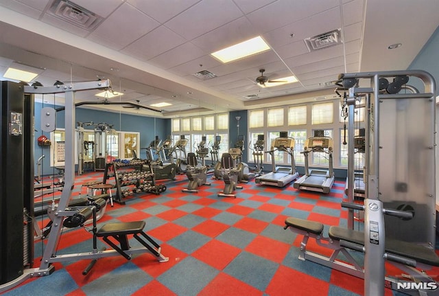 workout area featuring ceiling fan, plenty of natural light, and a drop ceiling