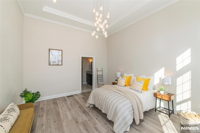 bedroom featuring crown molding, connected bathroom, light hardwood / wood-style floors, and a notable chandelier