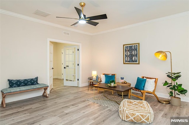 sitting room with wood-type flooring, ornamental molding, and ceiling fan