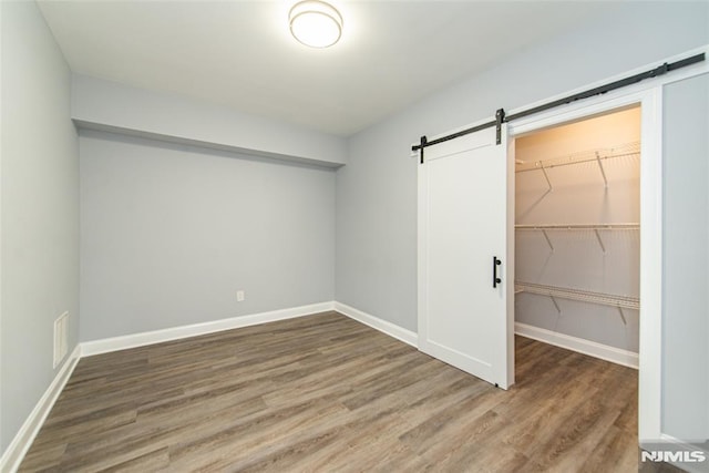 interior space with a barn door, hardwood / wood-style floors, and a closet